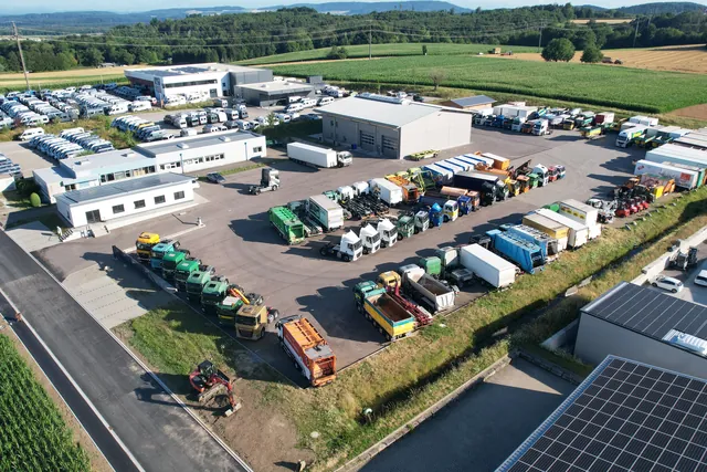 Luftaufnahme des Trucktrade-Geländes in Jestetten mit Halle, Solardächern und aufgereihten Lastwagen